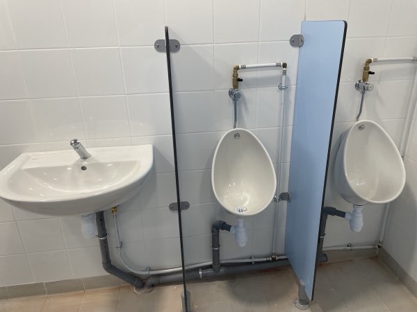 Urinoirs et lavabo installés dans des sanitaires collectifs